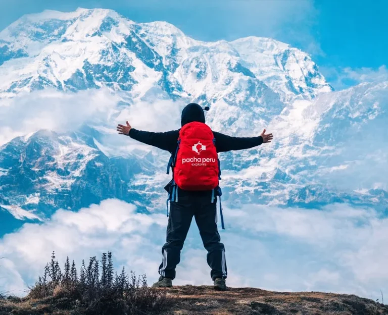 Hiker with Pacha Peru Explorers logo on red backpack overlooking the Andes mountains during an alternative Peru trek