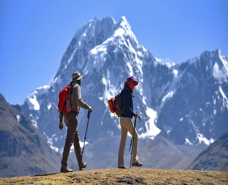 Hikers on the Ausangate Trek 5 Days route with snow-capped Ausangate mountain in Peru