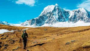 Hiker trekking through high-altitude landscapes with snow-capped Ausangate mountains in Peru