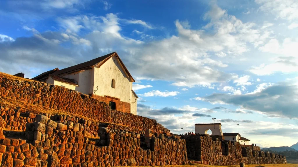 Stone walls of Chinchero Inca ruins overlooking Cusco at sunset