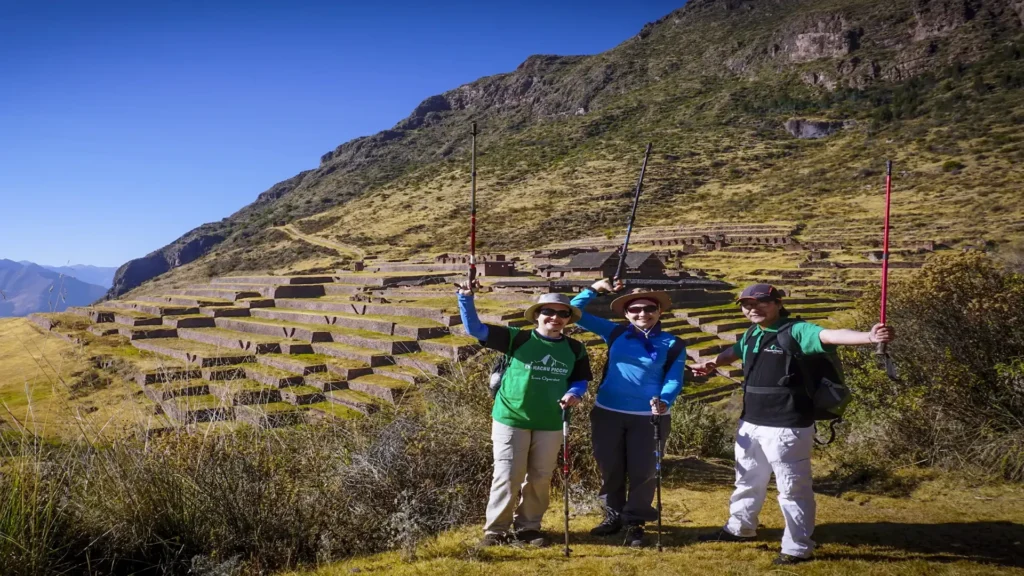 Group of hikers celebrating at Huchuy Qosqo Inca terraces in the Sacred Valley near Cusco, Peru.