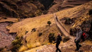 Hikers walking along the Inca trail path to Huchuy Qosqo during a full day trek from Cusco, Peru.