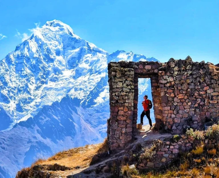 Hiker standing at Intipunku (Sun Gate) in Ollantaytambo with snowy mountains in the background, Cusco Peru.