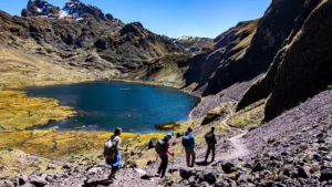 Hikers trekking above an alpine lake in the Peruvian Andes on the Lares Trek