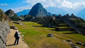 Tourist exploring the lower sector of Machu Picchu with terraces and mountains