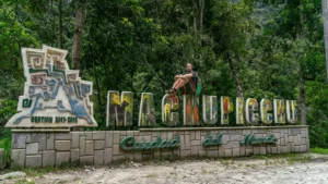 Traveler posing at Machu Picchu Pueblo sign on the Machu Picchu by Car route through Hidroelectrica