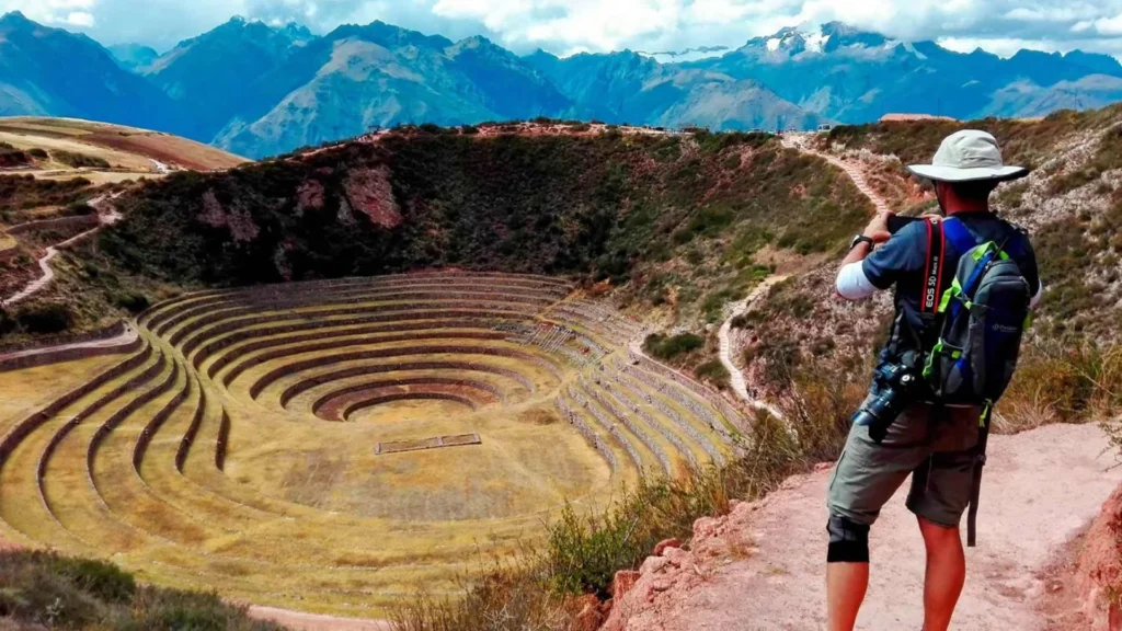 Traveler photographing the Moray Inca terraces in the Sacred Valley of Peru