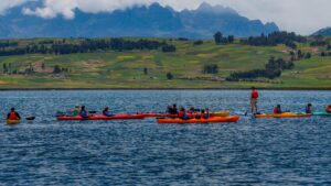 Group of travelers kayaking on a scenic Andean lake surrounded by green fields and mountain landscapes in Peru.