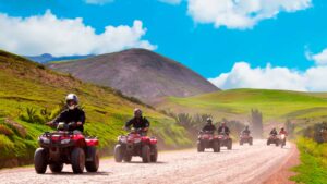 Group riding red ATVs on a scenic dirt road during the Maras Moray ATV Tour in the Sacred Valley of Cusco, Peru.