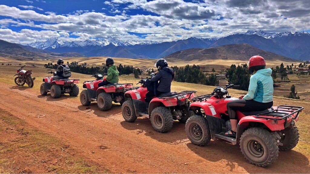 Group riding red ATVs with Andean mountains in the background during the Maras Moray ATV Tour in Cusco, Peru.
