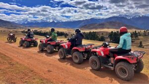 Group riding red ATVs with Andean mountains in the background during the Maras Moray ATV Tour in Cusco, Peru.