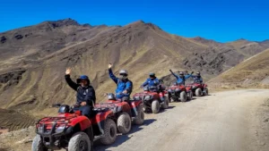 Group of travelers riding red ATVs toward Rainbow Mountain (Vinicunca) in the Andes of Cusco, Peru.