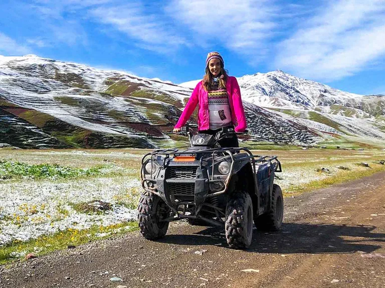 Traveler riding an ATV near Rainbow Mountain (Vinicunca) surrounded by colorful Andean landscapes in Cusco, Peru.