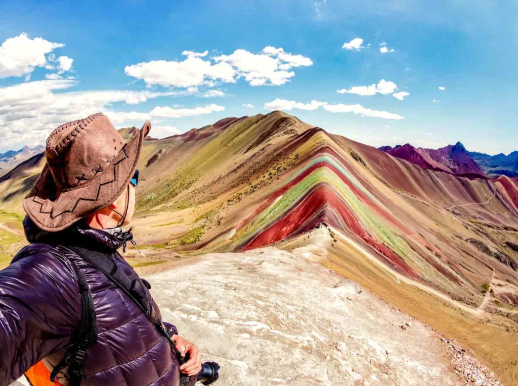 Traveler overlooking Rainbow Mountain (Vinicunca) with its colorful striped slopes in the Andes of Cusco, Peru.