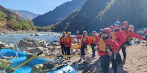 Group of adventure travelers wearing helmets and life jackets preparing for rafting on a river in the Sacred Valley near Cusco, Peru.