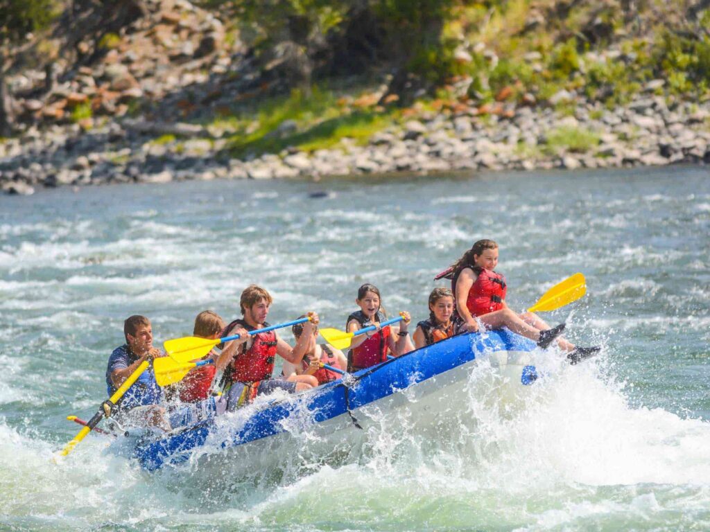 Group of adventure travelers paddling through strong white water rapids on the Urubamba River in Cusco, Peru.