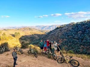 Group of cyclists posing with mountain bikes on a scenic viewpoint in Yuncaypata near Cusco, Peru.