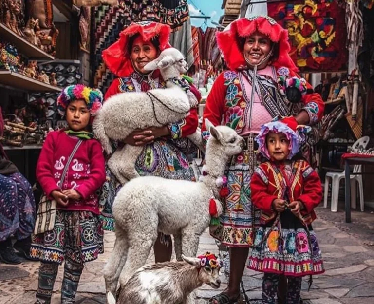 Andean women in traditional clothing with alpacas at Pisac market in the Sacred Valley of Peru