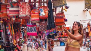 Tourist shopping handmade Andean textiles at Pisac Market in the Sacred Valley, Cusco Peru
