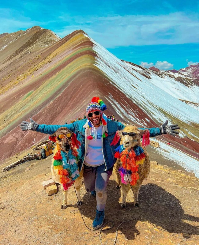 Tourist posing with llamas at Rainbow Mountain Vinicunca in Peru