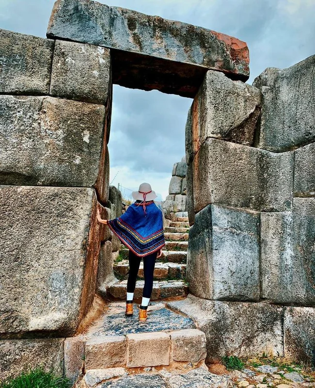 Traveler walking through the massive Inca stone gate at Sacsayhuamán near Cusco