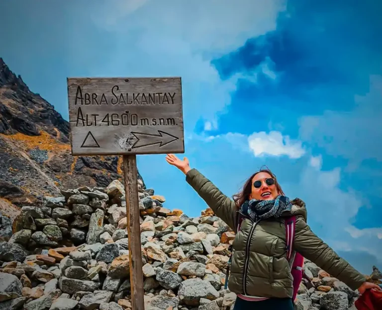 Hiker celebrating at Salkantay Pass sign at 4,600 meters above sea level in Peru