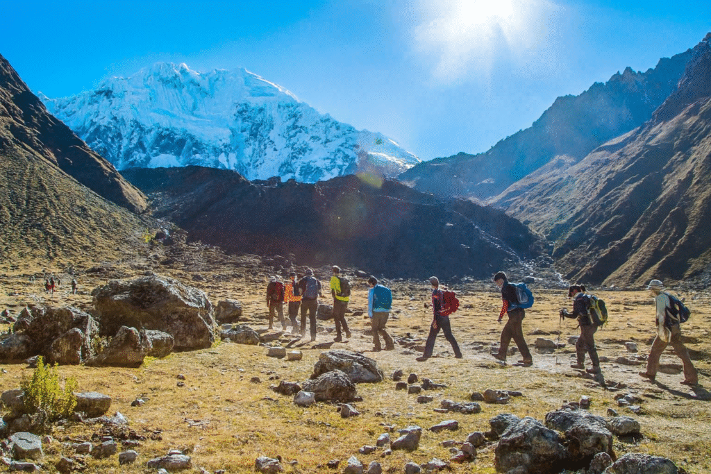 Group of hikers walking through an Andean glacier valley during the Salkantay Trek Challenge 3 Days, with snowy mountains and bright sunlight