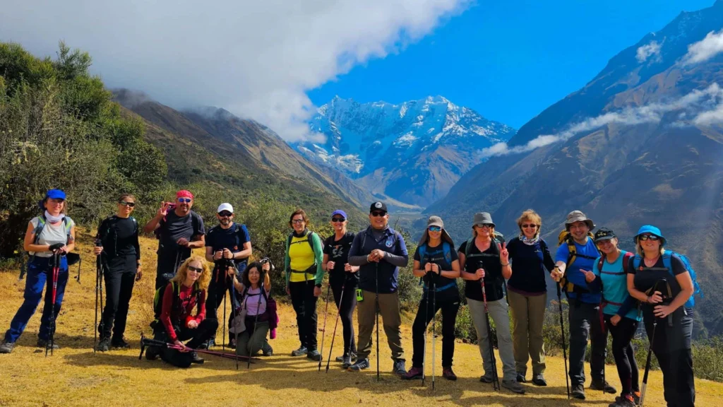 Group of hikers standing on the Salkantay Trek trail with snow-capped mountains behind them in the Peruvian Andes