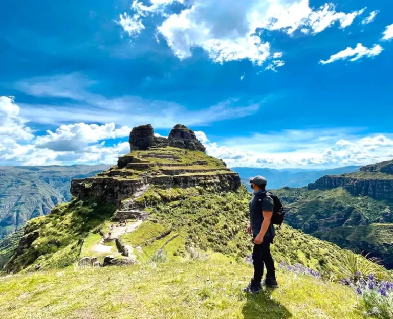 Tourist looking at the Waqrapukara archaeological site during a one day trek in Cusco, Peru.