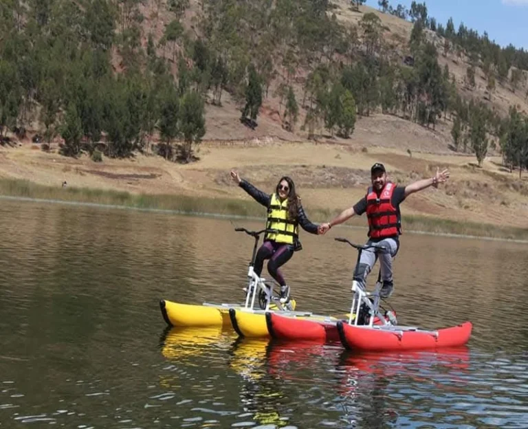 Couple enjoying a water bike experience on a lake in Peru wearing life jackets.