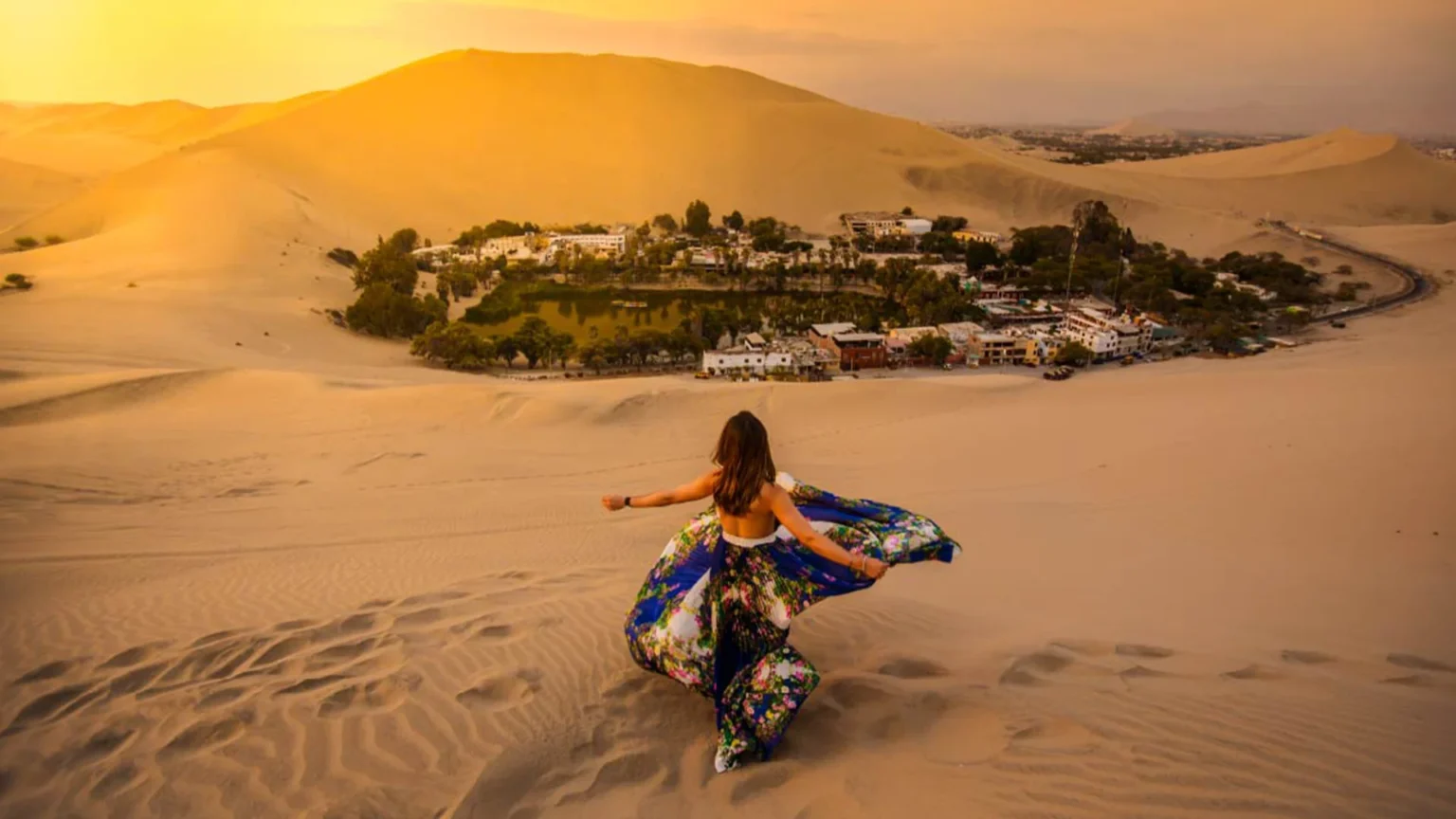 Tourist enjoying sunset view over Huacachina oasis surrounded by sand dunes in Ica Peru