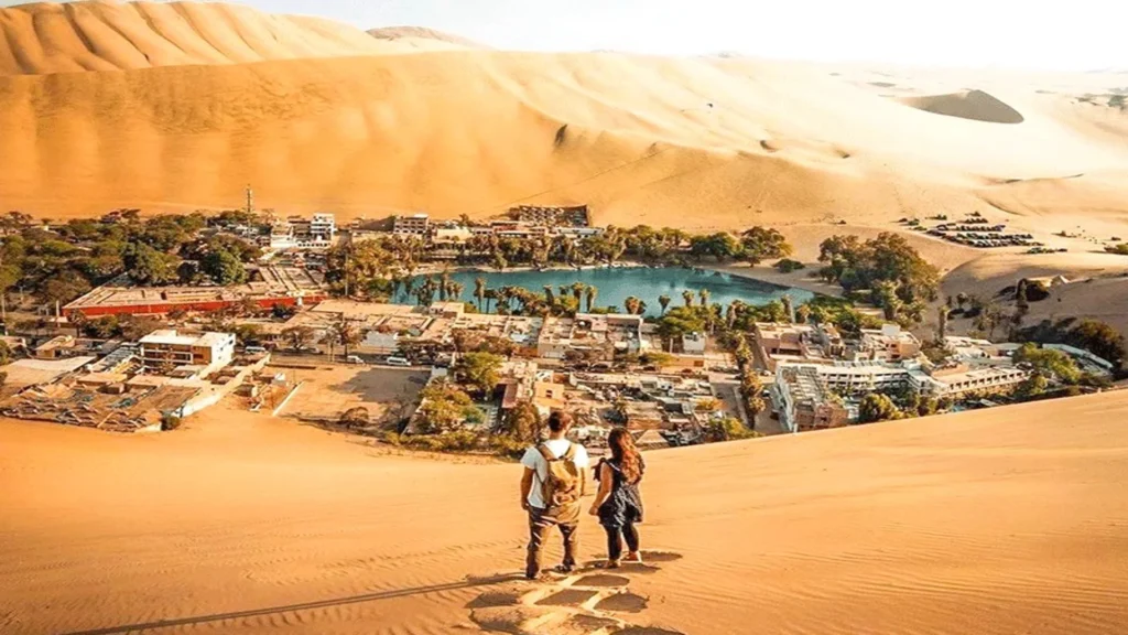 Tourists overlooking Huacachina oasis surrounded by sand dunes in Ica Peru