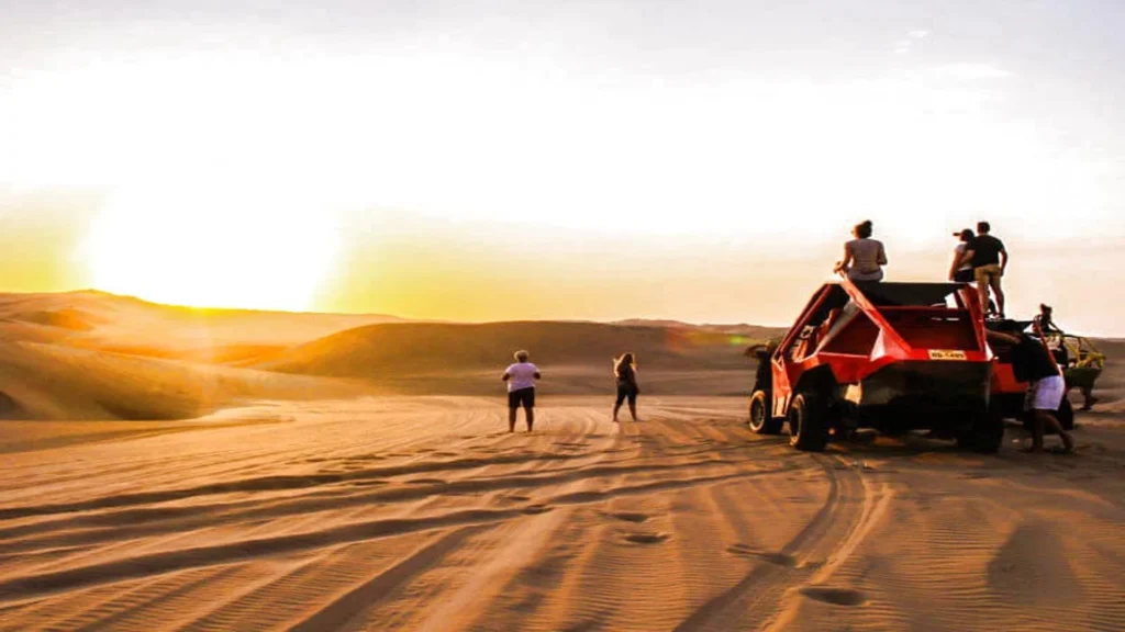 Tourists watching sunset near a dune buggy in Huacachina desert Ica Peru