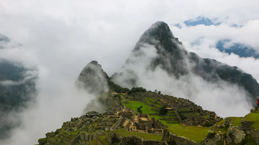 Machu Picchu ruins surrounded by clouds and mist during February rainy season in Cusco Peru